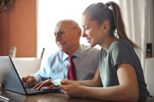 Young lady and old man looking at a computer
